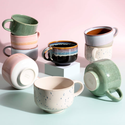 Collection of colorful ceramic mugs on a pastel background