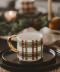 Plaid mug on a black tray with a blurred festive background