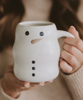 Person holding a snowman-shaped ceramic mug