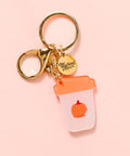 Keychain with a pumpkin-themed cup charm on a pink background