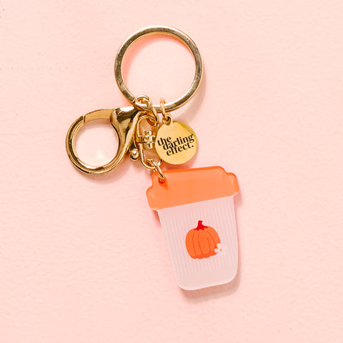 Keychain with a pumpkin-themed cup charm on a pink background