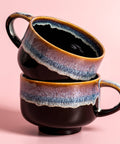 Two ceramic mugs with a gradient finish on a pink background