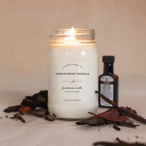 Sandalwood Vanilla candle in a glass jar with vanilla beans and a bottle of vanilla extract on a beige background