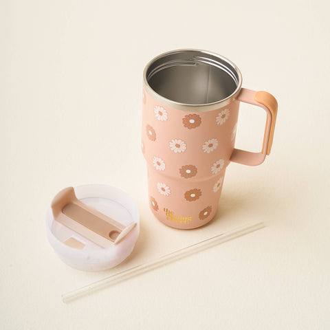 A tan insulated travel mug with a floral pattern, shown with its white lid and a clear straw on a light beige background.