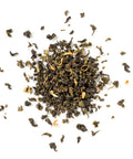 Dry green tea leaves scattered on a white background