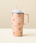 A tan-colored insulated travel tumbler with a handle, decorated with a pattern of white and brown daisies. It features a light blue lid with a clear straw, set against a minimalist beige background.