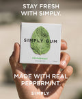 Hand holding a box of Simply Gum with text 'Stay fresh with Simply' and 'Made with real peppermint'.